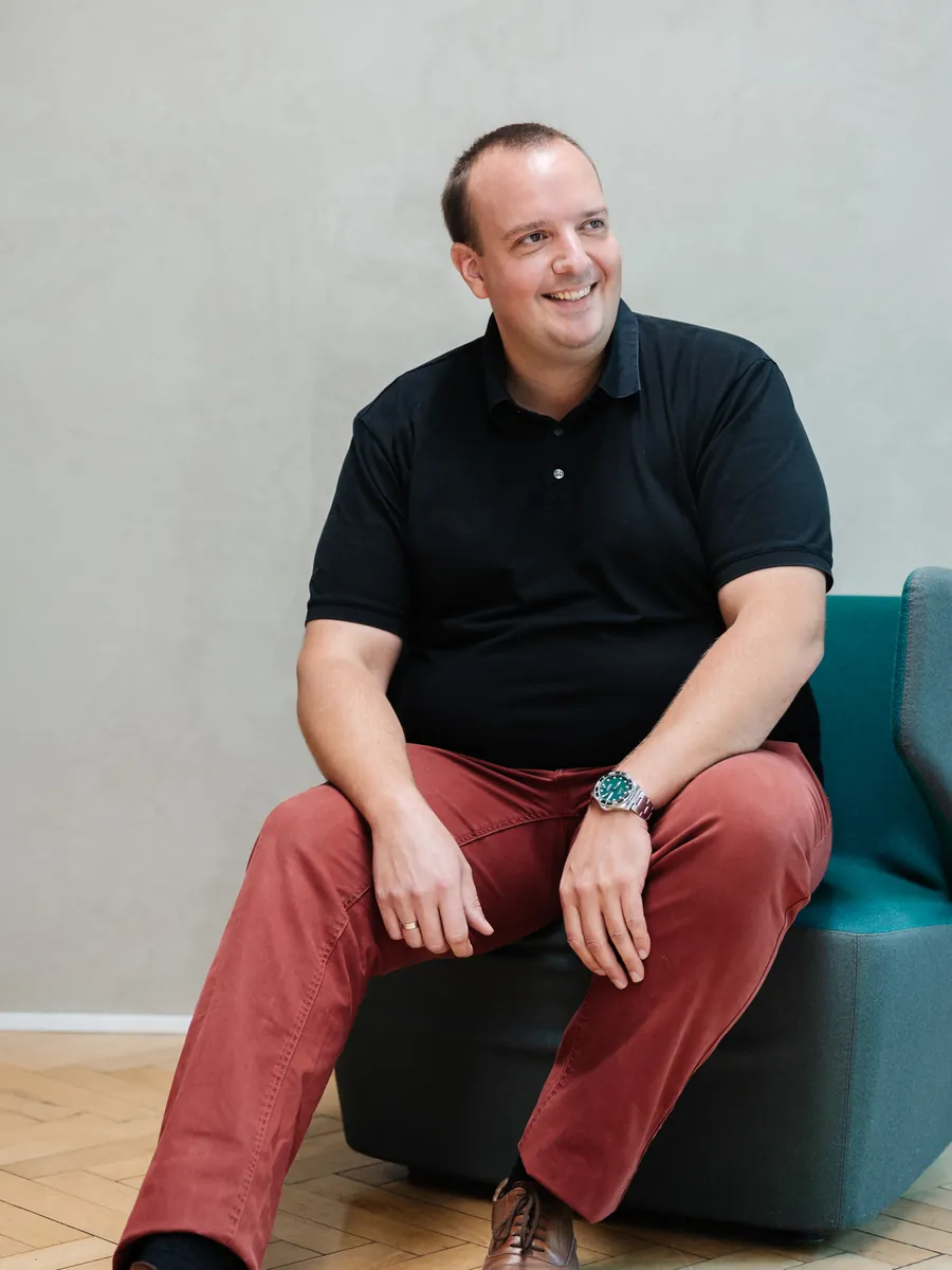 Fabian Becker sitzt lächelnd in einem Sessel im Ausstellungsraum