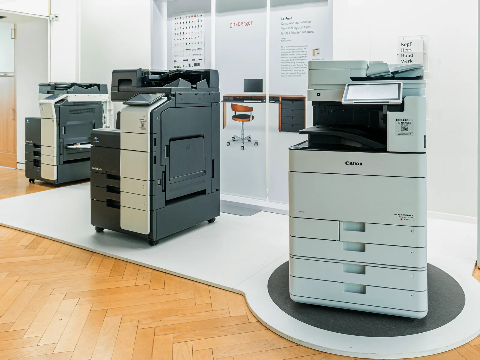 Der Ausstellungsraum von Ordnung Trier mit mehreren Multifunktionsgeräten von Canon und Konica Minolta auf einem weißen Podest